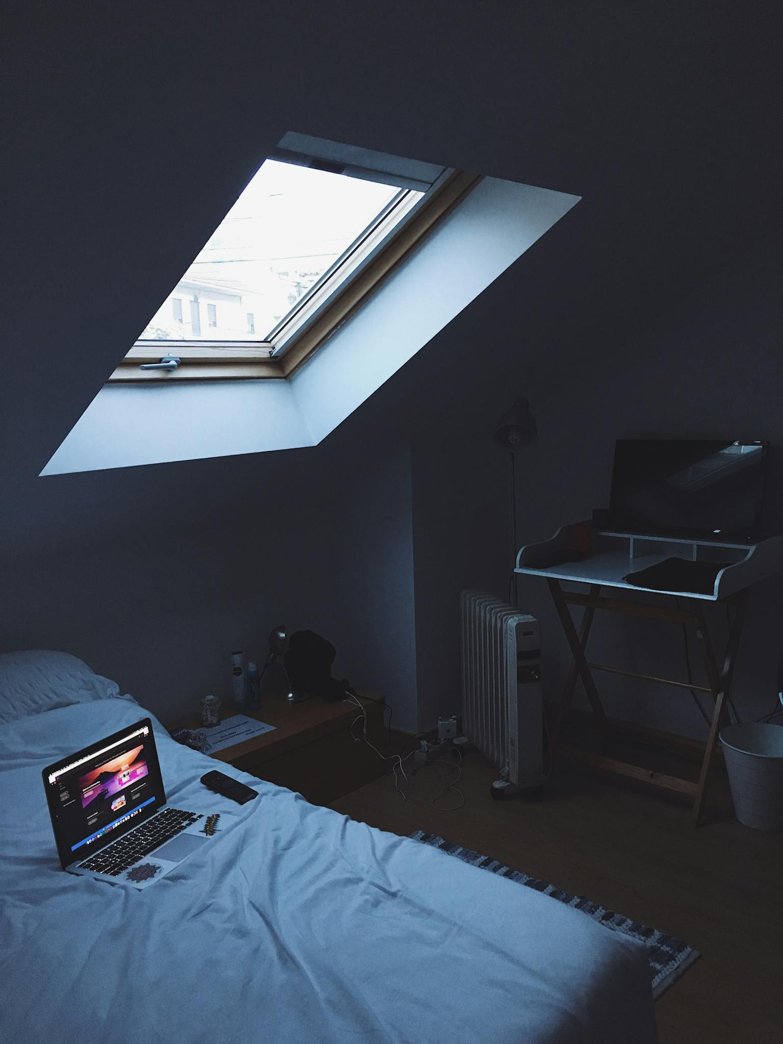 A modern home office setup in a cozy attic bedroom with skylight.