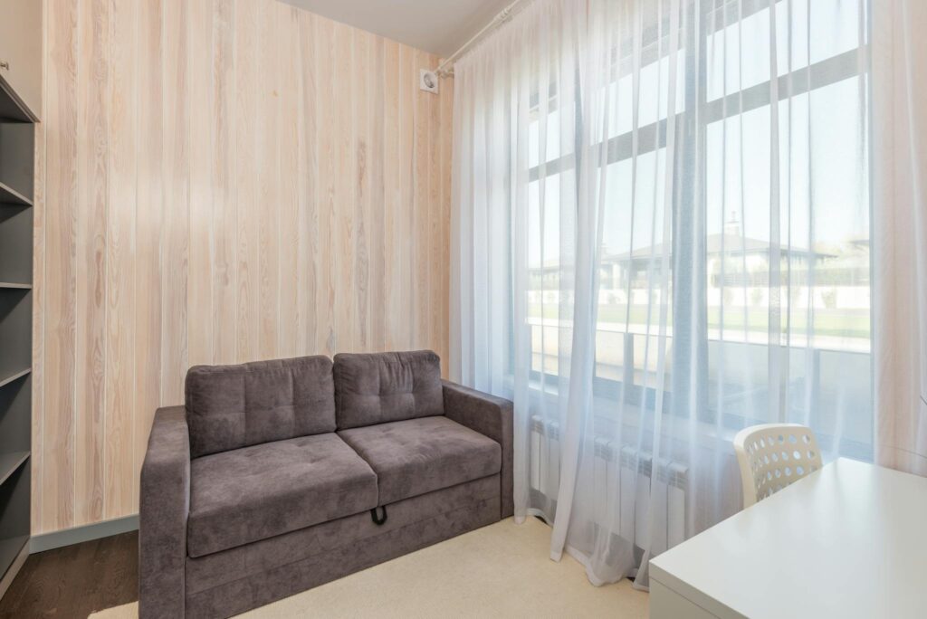 Bright apartment interior featuring a modern sofa and large window.