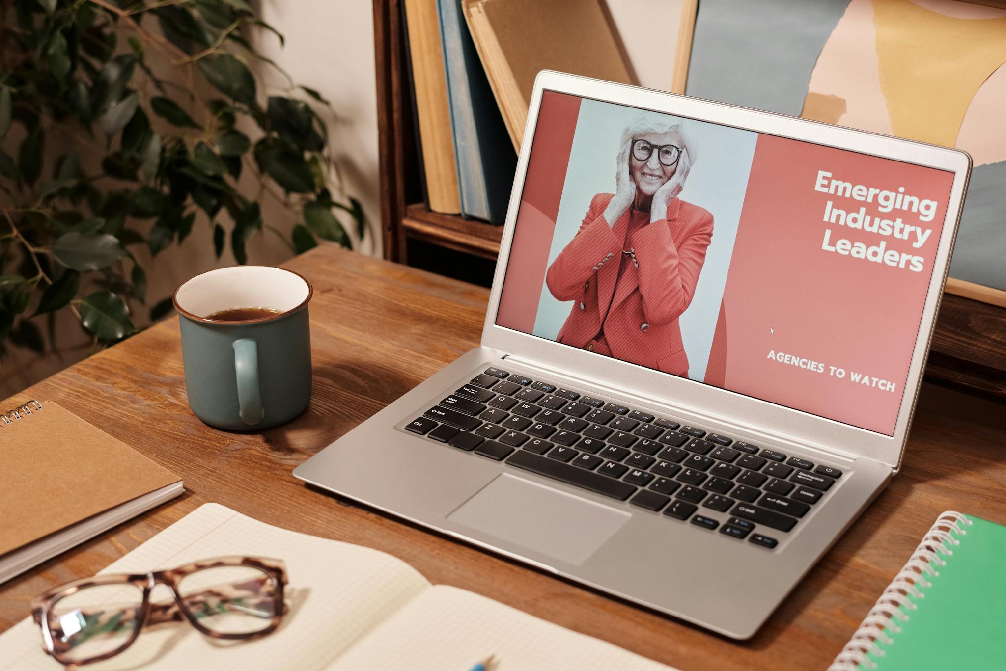 Cozy office desk with a laptop displaying 'Emerging Industry Leaders' and coffee mug.