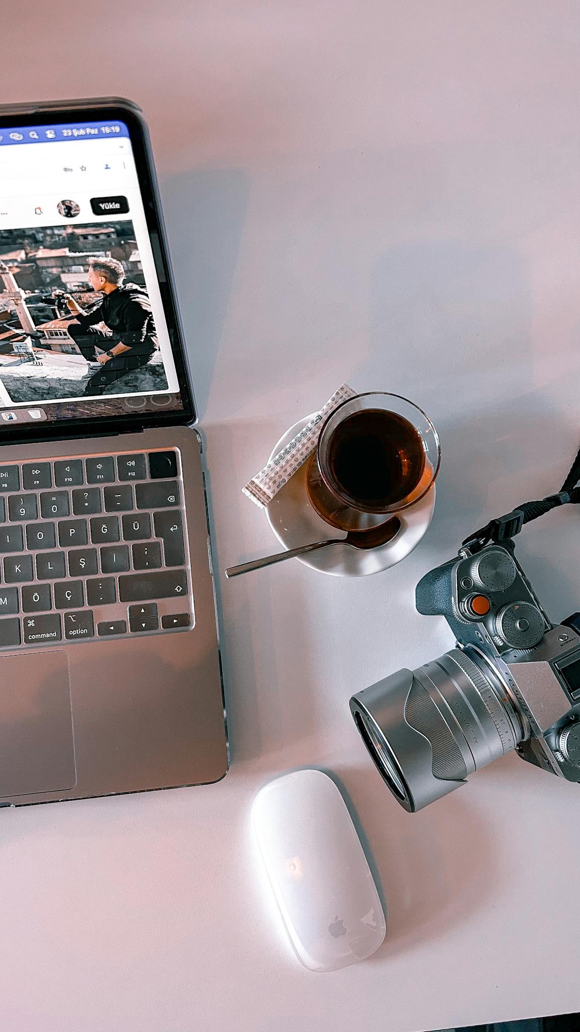 Modern workspace with laptop, camera, and tea in an artistic flat lay.